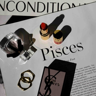 Stilvolles Beauty-Flatlay mit YSL-Parfüm, Lippenstifte und Schmuck auf einer Magazinseite mit Sternzeichen Pisces - Luxuriöse Kosmetikprodukte in moderner Inszenierung für den ultimativen Parfüm-Test