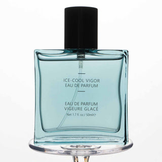 "Eleganter Glasflakon mit Ice-Cool Vigor Eau de Parfum in türkisblauer Farbe mit schwarzem Verschluss, 50ml Inhalt, auf transparentem Ständer präsentiert.