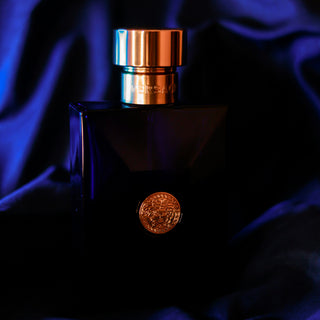 Luxuriöse schwarze Parfümflasche mit goldenem Medusa-Emblem von Versace auf dunkelblauem Seidenhintergrund, elegant beleuchtet mit kupferfarbenem Verschluss