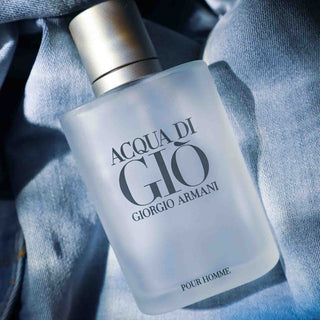 Acqua di Gio Pour Homme von Giorgio Armani, klassischer Herrenduft in mattierter Glasflasche mit silbernem Verschluss auf grauem Stoffhintergrund