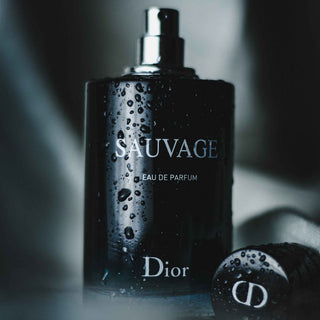 Schwarze Flasche Dior Sauvage Eau de Parfum mit Wassertropfen, daneben CD-Verschlusskappe, elegante Produktfotografie