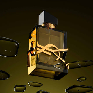 Luxuriöses YSL Parfum-Flakon in goldener Farbe auf dunklem Hintergrund mit Wassertropfen, künstlerisch inszeniert mit dem ikonischen YSL-Logo in eleganter Beleuchtung